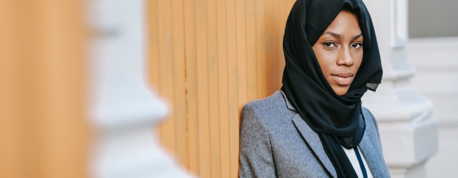 elegant black islamic woman messaging on smartphone and looking at camera